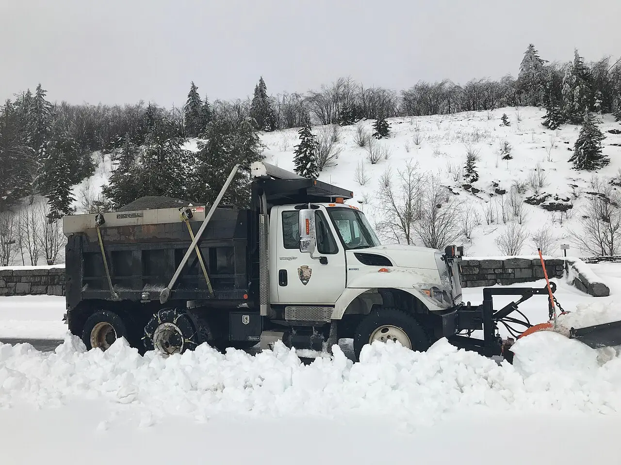 Snow plow truck clearing a snow covered parking lot, illustrating warehouse loading dock clearing in Chester